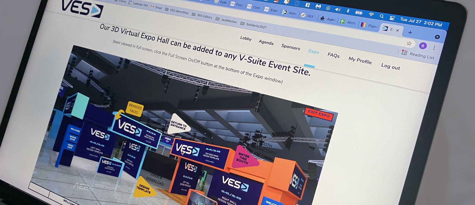 A laptop showing the VES Live 3D virtual expo hall with branded sponsor booths